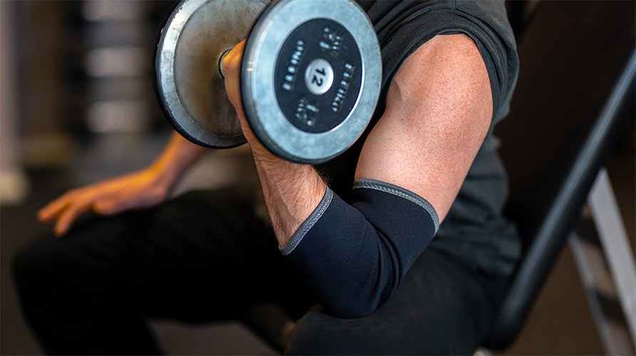 En mand l�fter en h�ndv�gt imens han har en albuebeskytter p�.